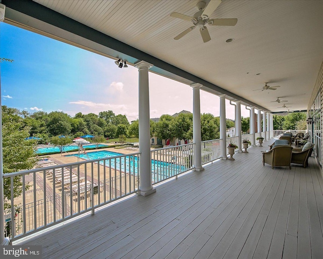 wooden deck with a ceiling fan and a community pool