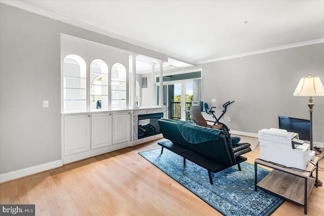 living area featuring crown molding, baseboards, a fireplace, and light wood-type flooring