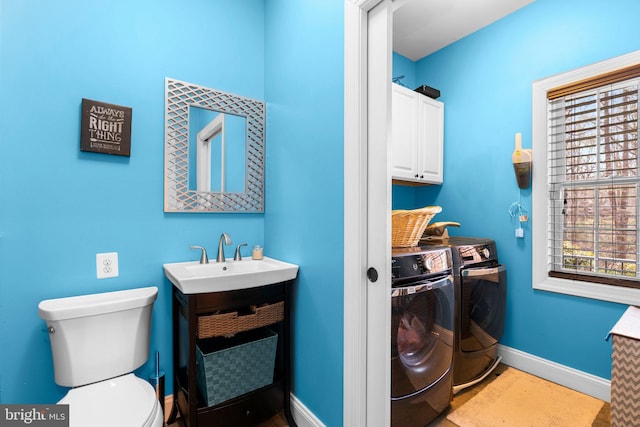 clothes washing area featuring independent washer and dryer, a sink, and baseboards