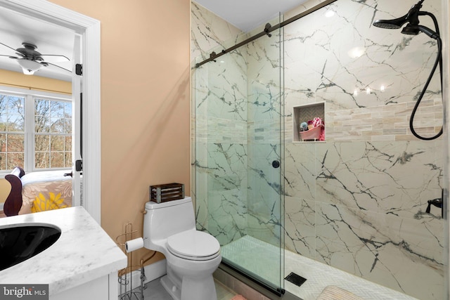 bathroom featuring toilet, ceiling fan, vanity, and a marble finish shower
