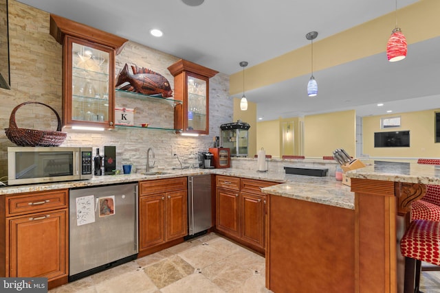 kitchen with brown cabinets, a sink, a peninsula, and appliances with stainless steel finishes