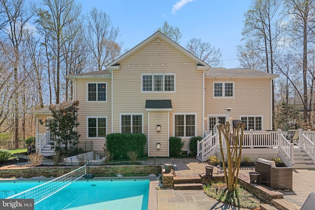 rear view of house with an outdoor pool, a deck, and a patio