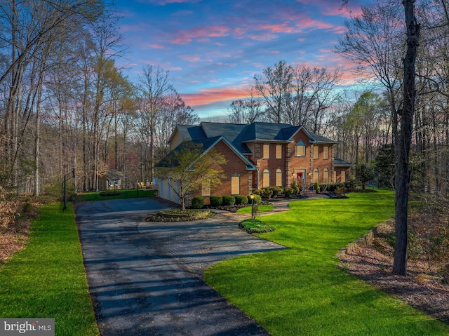 colonial home featuring brick siding, driveway, and a front lawn