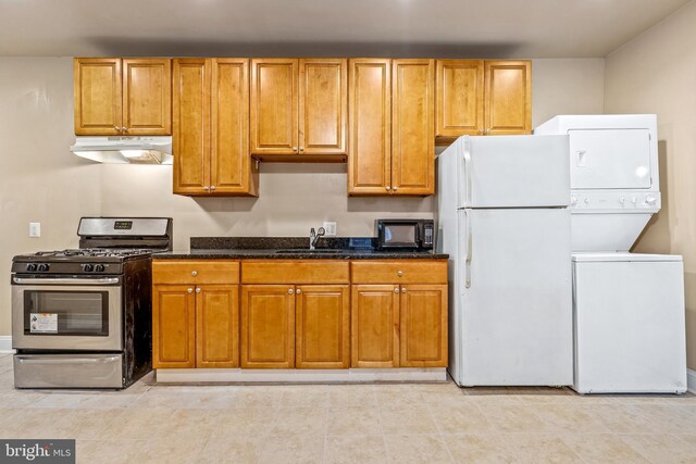 1508 V St SE, Washington, DC 20020 - kitchen featuring freestanding refrigerator, stacked washer and clothes dryer, stainless steel range with gas cooktop, under cabinet range hood, and black microwave