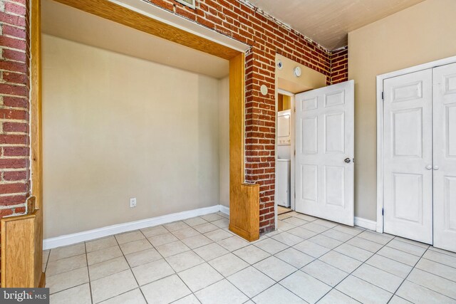 1508 V St SE, Washington, DC 20020 - unfurnished bedroom with brick wall, light tile patterned floors, a closet, and baseboards