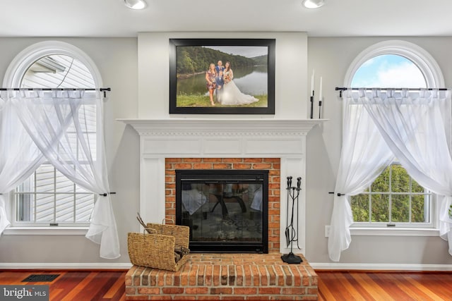 interior details featuring visible vents, baseboards, wood finished floors, and a fireplace