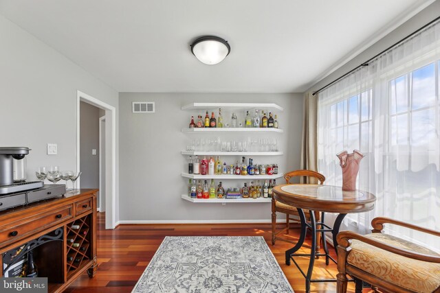 interior space with wood finished floors, baseboards, a dry bar, and visible vents