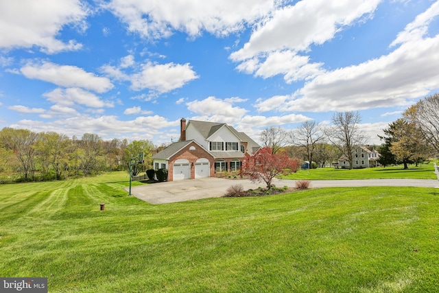 view of front of home featuring a front yard, brick siding, a chimney, and curved driveway