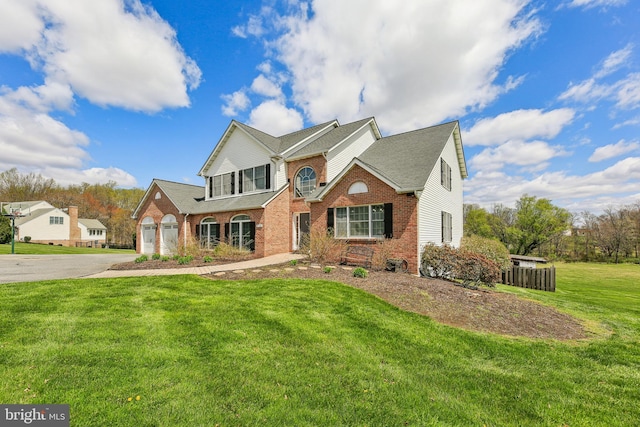 traditional-style house with driveway, a front yard, a garage, and brick siding