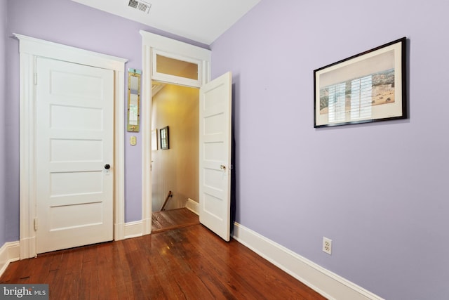 unfurnished bedroom with visible vents, dark wood-style flooring, and baseboards