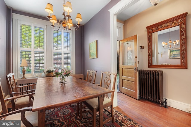 dining area with radiator heating unit, baseboards, an inviting chandelier, and wood finished floors