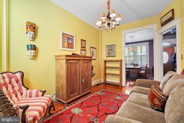 living room featuring an inviting chandelier, baseboards, and wood finished floors