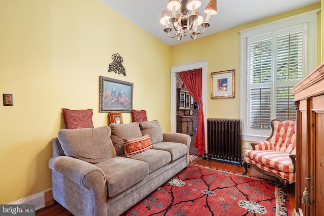 living room featuring radiator heating unit, baseboards, wood finished floors, and a notable chandelier