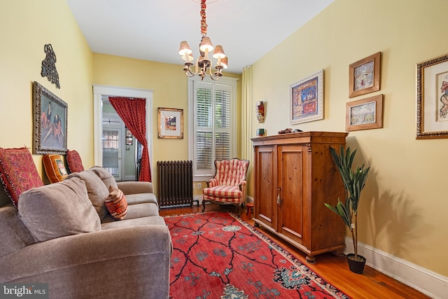 living area featuring baseboards, an inviting chandelier, radiator heating unit, and wood finished floors