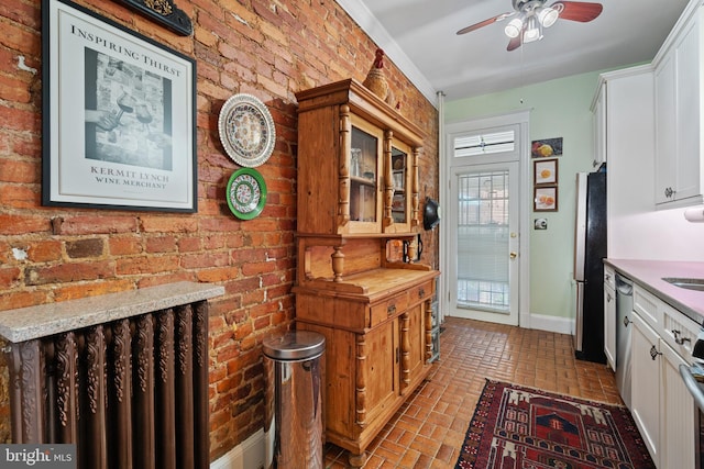 kitchen featuring baseboards, ceiling fan, white cabinetry, brick floor, and appliances with stainless steel finishes