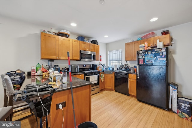kitchen with a peninsula, light wood finished floors, dark countertops, recessed lighting, and black appliances