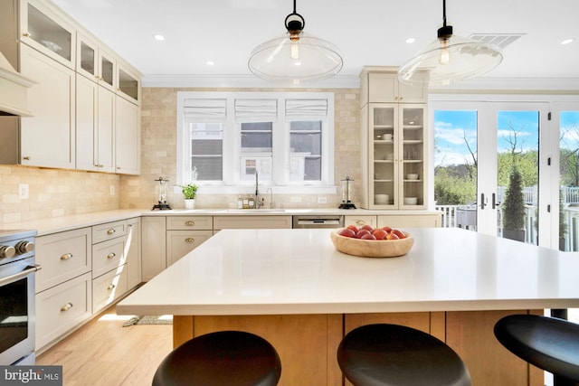 kitchen with a sink, stainless steel range oven, crown molding, a breakfast bar, and tasteful backsplash