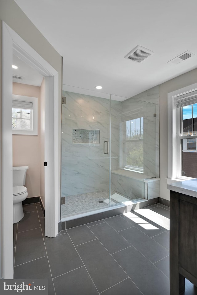 bathroom featuring a marble finish shower, toilet, baseboards, tile patterned floors, and recessed lighting