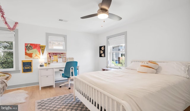 bedroom featuring light wood-style floors, ceiling fan, and an office area