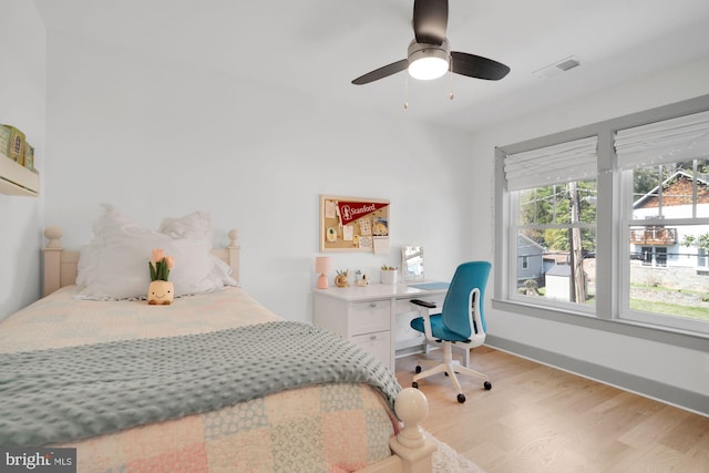 bedroom featuring light wood-type flooring, a ceiling fan, an office area, and baseboards