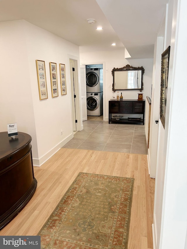 corridor with stacked washer and clothes dryer, wood finished floors, recessed lighting, and baseboards