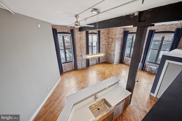 428 N 13th St Unit 5C, Philadelphia, PA 19123 - unfurnished dining area with brick wall, wood finished floors, ceiling fan, baseboards, and a sink