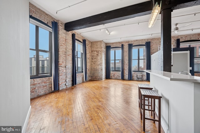 428 N 13th St Unit 5C, Philadelphia, PA 19123 - empty room with brick wall, rail lighting, hardwood / wood-style flooring, plenty of natural light, and beamed ceiling