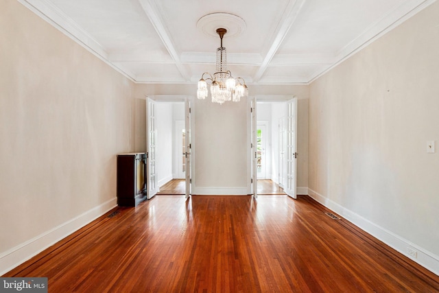 empty room featuring baseboards, beamed ceiling, wood finished floors, and a notable chandelier