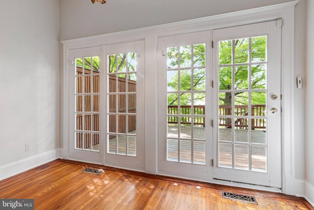 entryway with wood-type flooring, baseboards, and visible vents