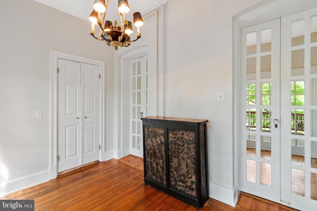 interior space featuring baseboards, a notable chandelier, french doors, and wood finished floors