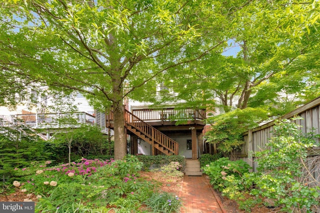 rear view of house with fence, a wooden deck, and stairs