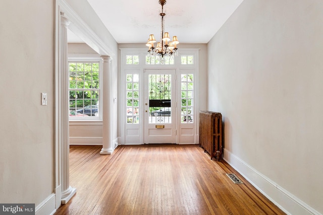 doorway to outside featuring an inviting chandelier, radiator, baseboards, and visible vents