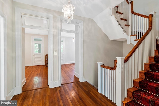 stairway with baseboards, wood-type flooring, and a chandelier