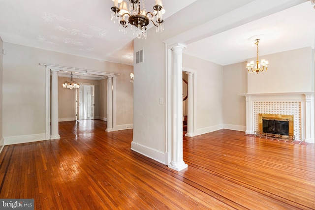 unfurnished living room with an inviting chandelier, a tiled fireplace, visible vents, and hardwood / wood-style floors