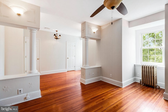 unfurnished room with radiator heating unit, a ceiling fan, ornate columns, visible vents, and hardwood / wood-style flooring