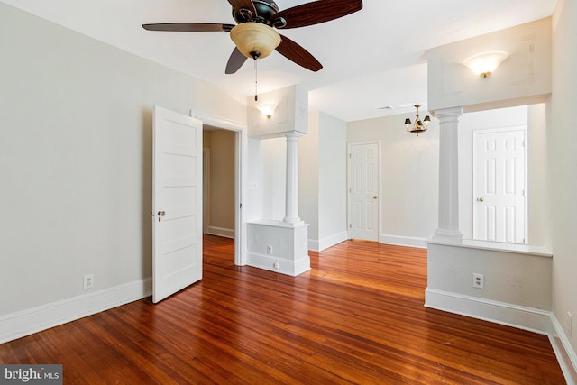 empty room featuring baseboards, ceiling fan, hardwood / wood-style flooring, and ornate columns