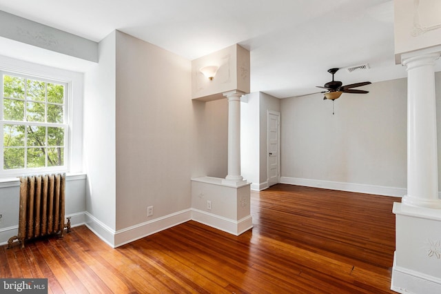 spare room featuring ornate columns, a ceiling fan, visible vents, and radiator heating unit