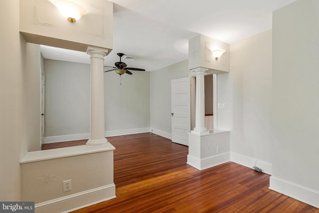 unfurnished room featuring a ceiling fan, baseboards, wood finished floors, ornate columns, and visible vents