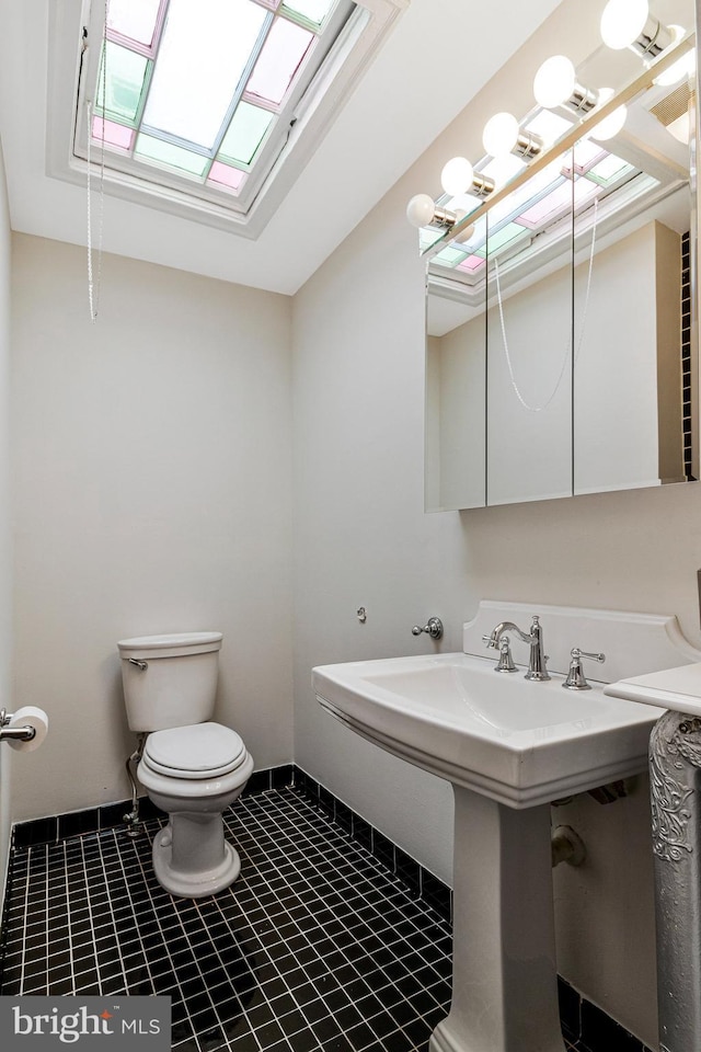 bathroom with toilet, a sink, and tile patterned flooring