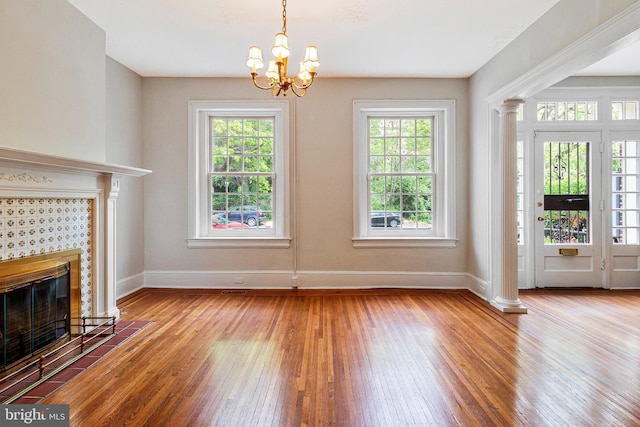unfurnished living room featuring baseboards, a wealth of natural light, and hardwood / wood-style floors