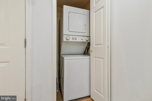 clothes washing area featuring stacked washer and clothes dryer and laundry area