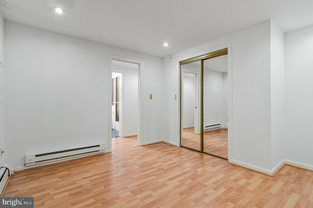 unfurnished bedroom with wood finished floors, a baseboard radiator, a closet, a baseboard heating unit, and recessed lighting
