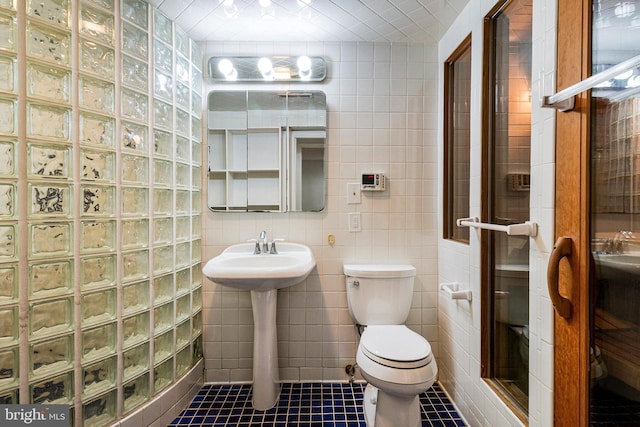 full bathroom with a sink, tile patterned flooring, toilet, tile walls, and a shower stall