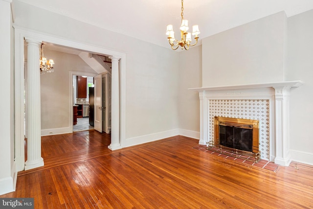 unfurnished living room featuring baseboards, a tile fireplace, hardwood / wood-style floors, and a chandelier