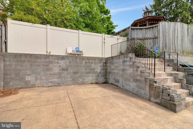 view of patio with fence and stairway