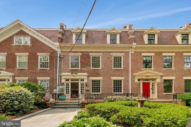 view of front of home with mansard roof and brick siding