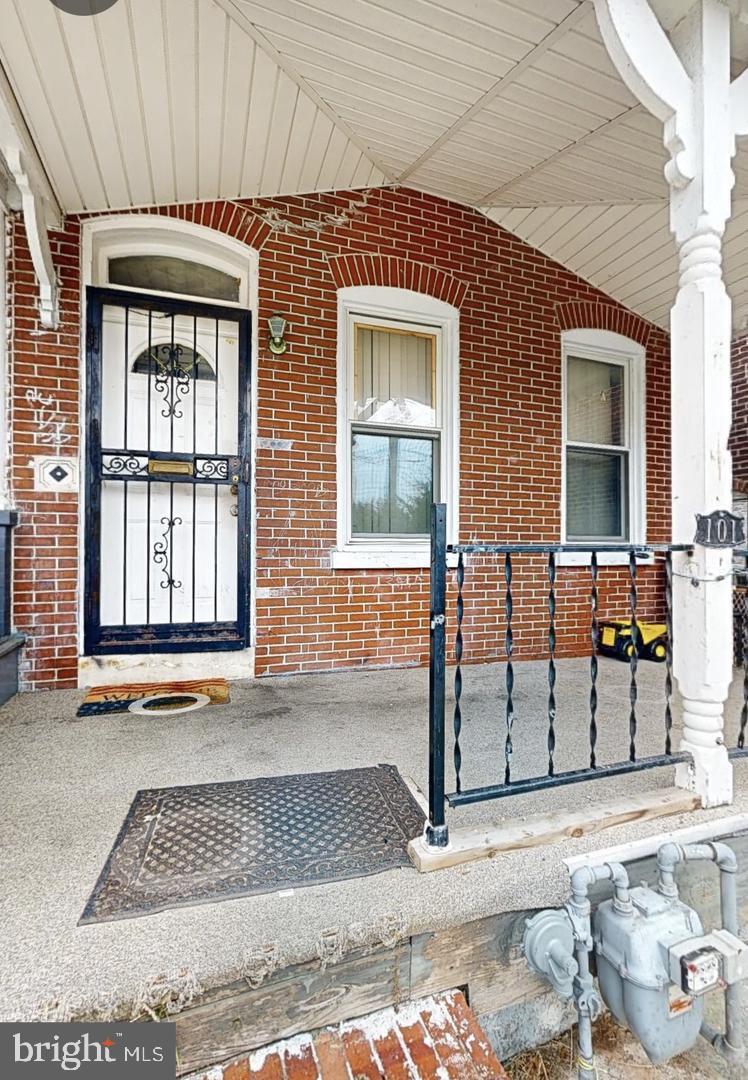 property entrance featuring brick siding and a porch