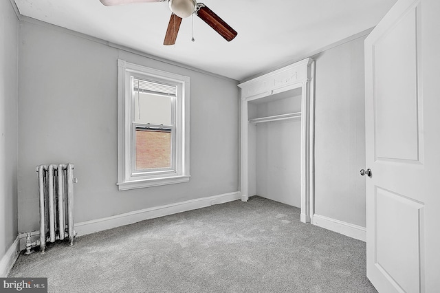 unfurnished bedroom featuring radiator heating unit, multiple windows, carpet, and baseboards