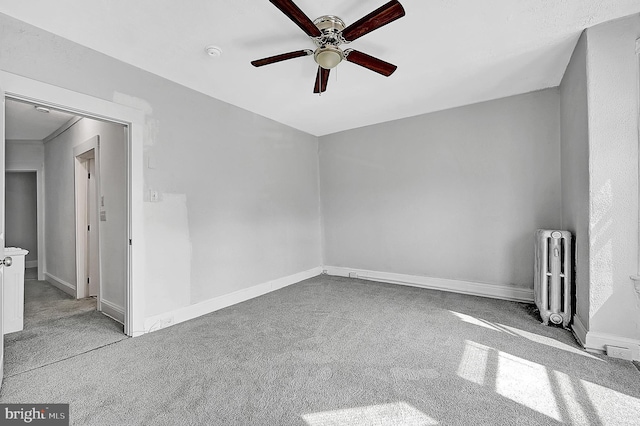 unfurnished room featuring ceiling fan, radiator heating unit, light carpet, and baseboards