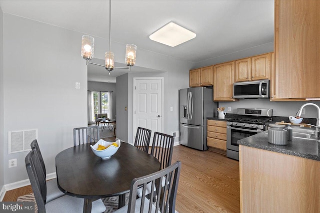 20973 Killawog Ter, Ashburn, VA 20147 - kitchen featuring stainless steel appliances, dark countertops, light wood finished floors, and light brown cabinets